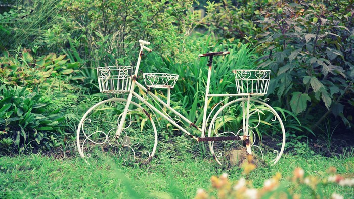 White bicycle planter in a garden