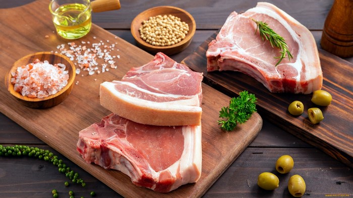 Raw pork chops with spices and olives on cutting boards