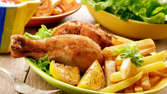 Fried chicken drumsticks with french fries and lemon wedges