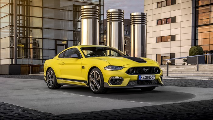 Yellow Ford Mustang Mach 1 parked in front of modern building