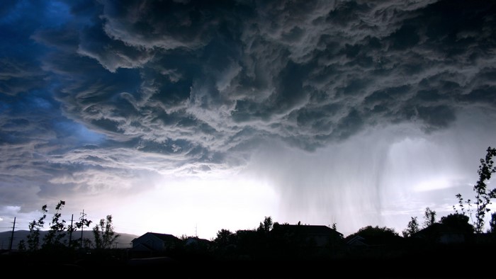 Dark storm clouds with rain over a silhouetted town