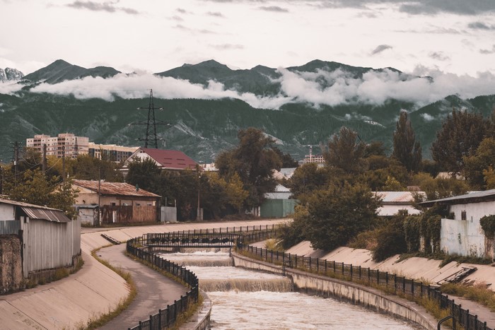 Cityscape with river and mountains under clouds