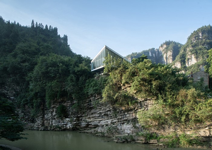 Modern glass house on a cliff overlooking a river