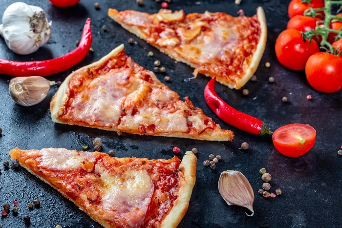Slices of pizza with tomatoes, garlic, and chili peppers