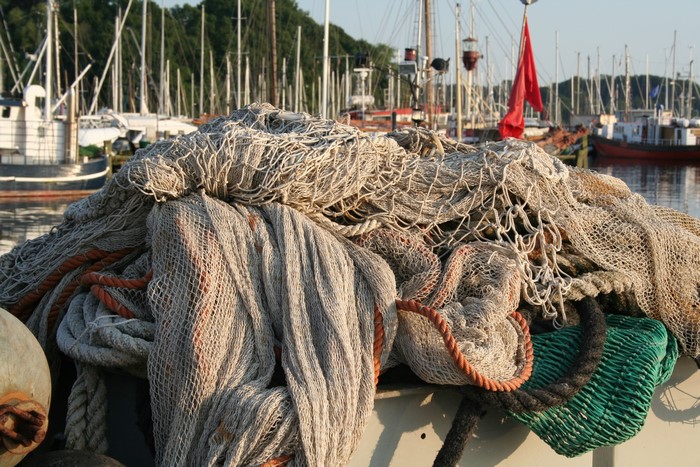 Fishing nets piled on a boat in a harbor