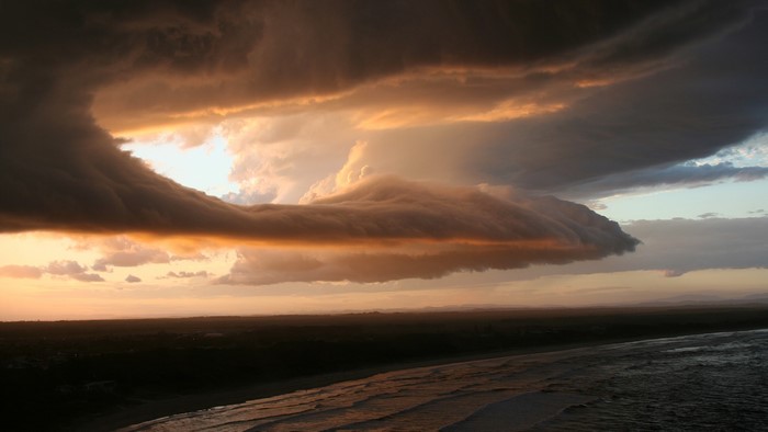 Dramatic storm clouds over a beach at sunset