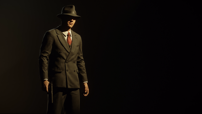 Man in suit and hat holding a gun