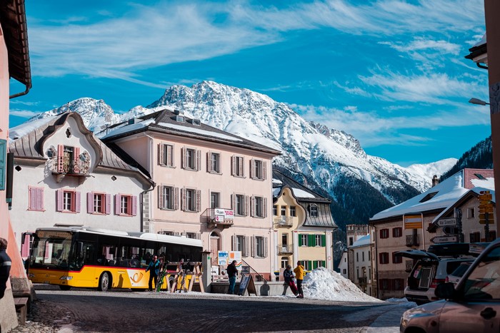 Yellow bus in a Swiss Alps village with snow-capped mountains
