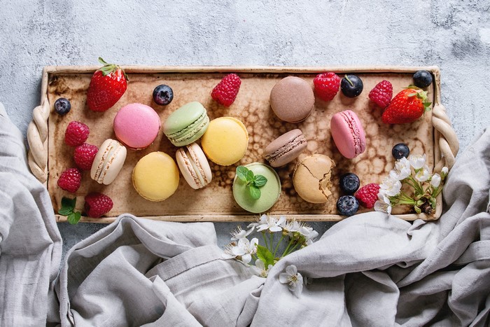 Colorful macarons with berries and strawberries on a tray