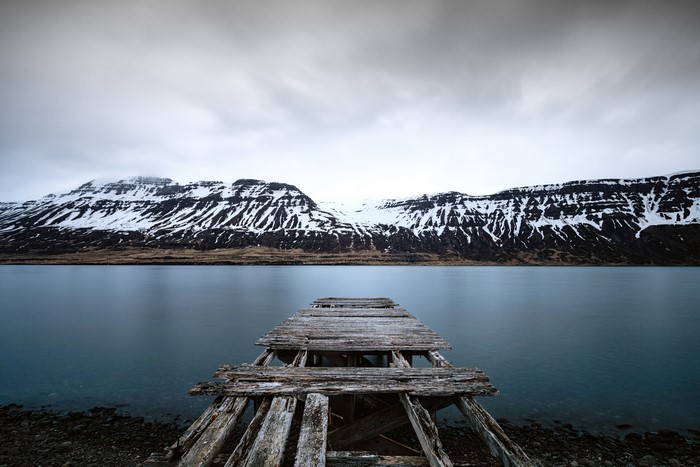 Old wooden pier on a lake with snow-capped mountains