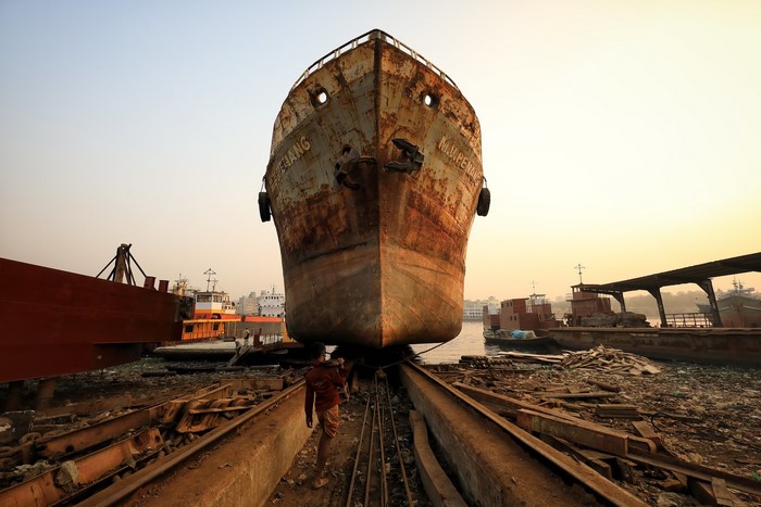 Rusted ship in a dry dock with a worker