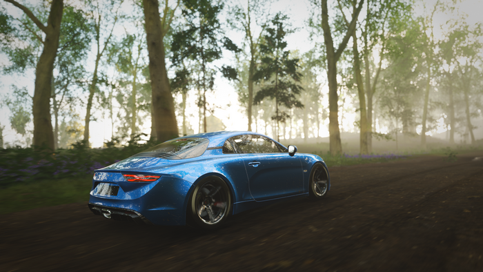 Blue Renault Alpine driving on a dirt road in a forest