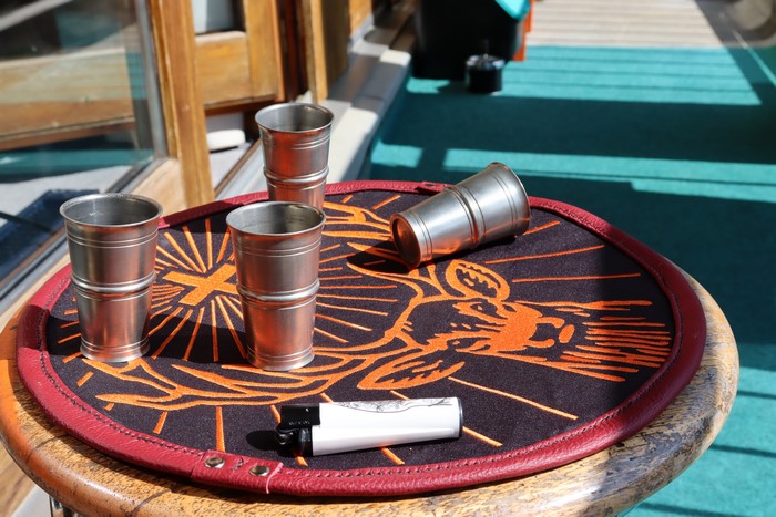 Four Jägermeister shot glasses and a lighter on a leather mat