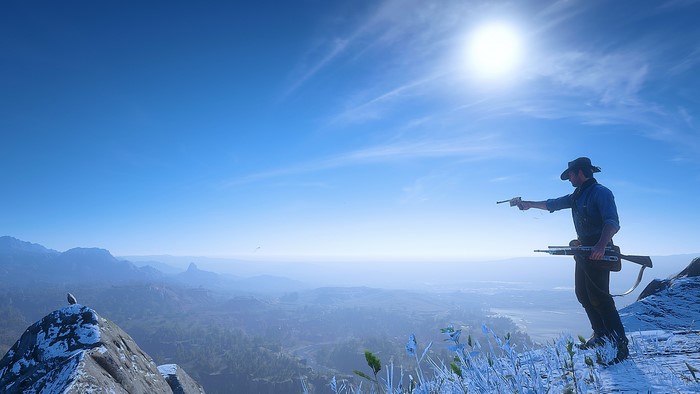 Man with guns on mountain overlooking landscape in Red Dead Redemption 2