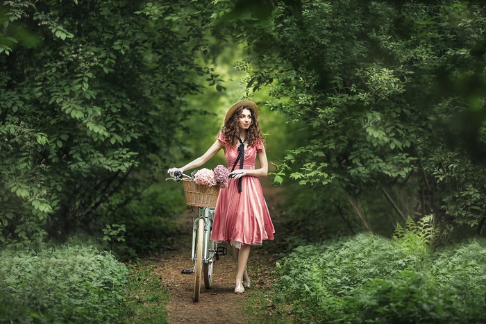 Woman in pink dress with bicycle in forest