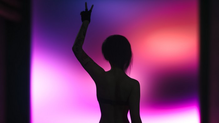 Woman with arms up in front of colorful background