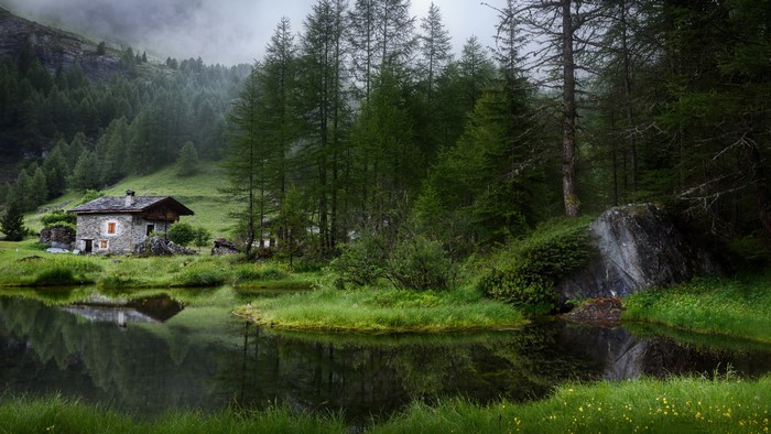 Stone house by a lake in a green forest