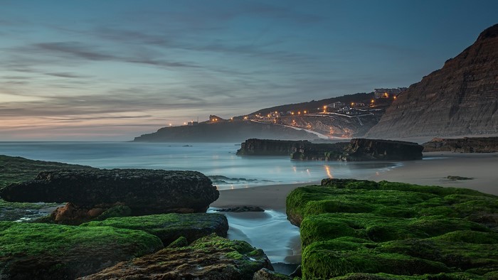 Coastal village at dusk with moss-covered rocks