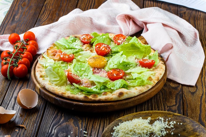 Caesar salad pizza with cherry tomatoes and egg yolk
