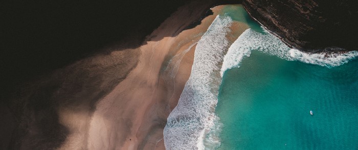 Aerial view of a sandy beach and turquoise ocean with waves