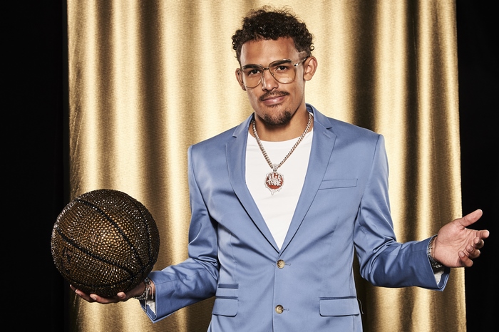 Trae Young in a blue suit holding a jeweled basketball