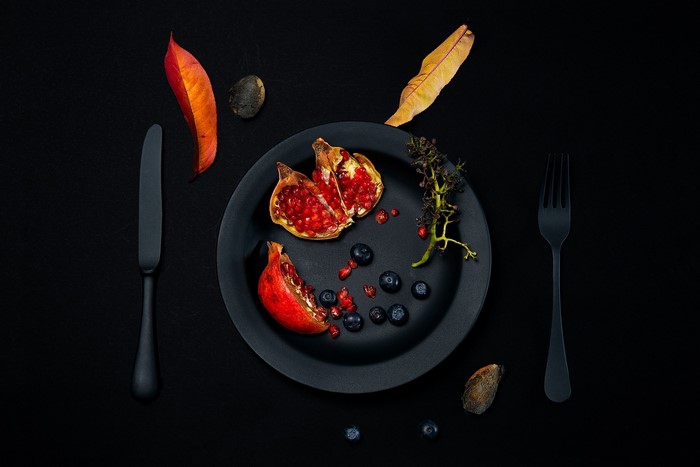 Still life with pomegranate, blueberries, and autumn leaves
