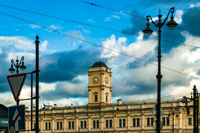 Building with clock tower and street lamps under cloudy sky