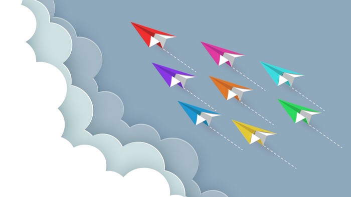 Colorful paper planes flying through clouds