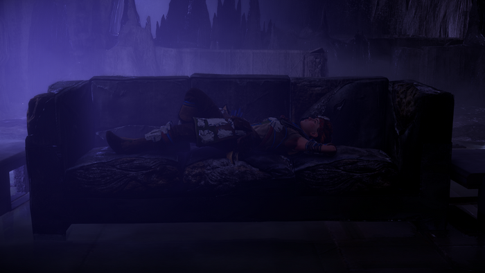 Aloy from Horizon Zero Dawn lying on a couch in a cave