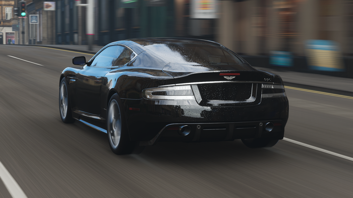 Black Aston Martin DBS driving on a city street
