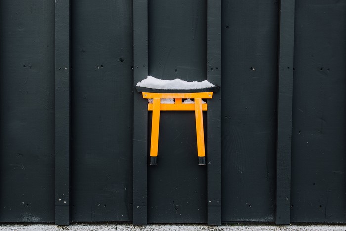 Orange Torii gate with snow on a dark wooden wall
