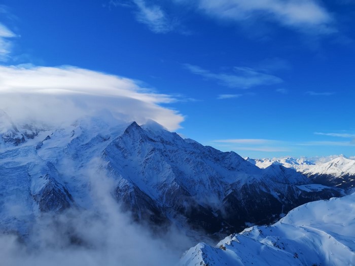 Snowy mountains under a blue sky with clouds