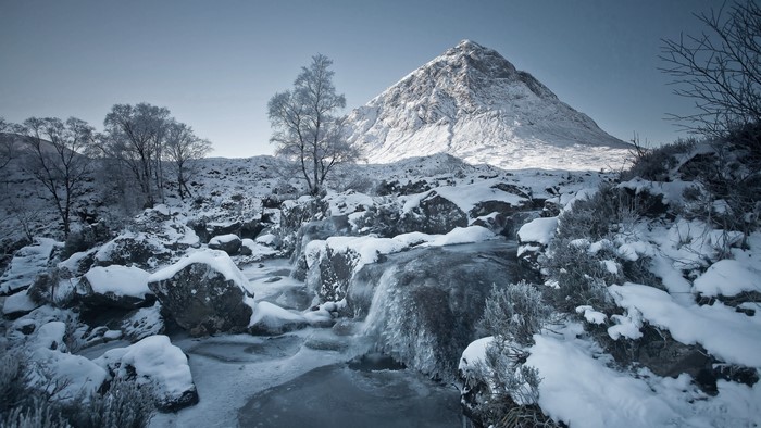 Winter landscape with snow-covered mountain and frozen stream