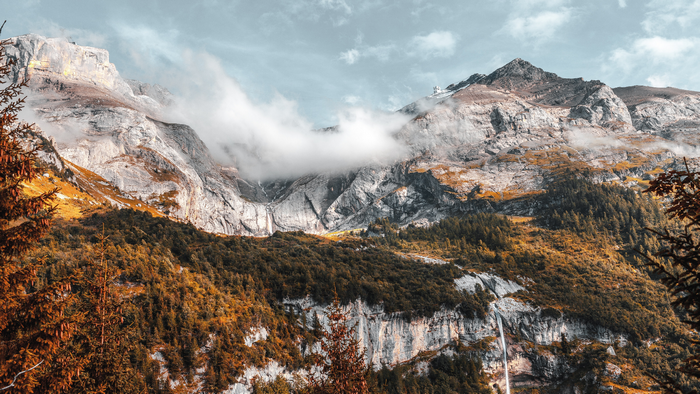 Majestic mountains with clouds and autumn trees