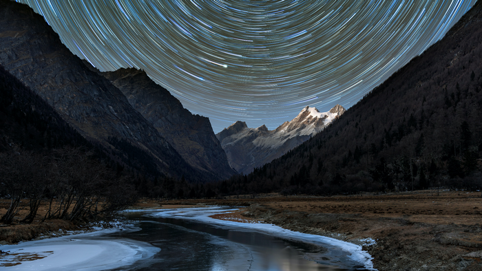 Star trails over mountains and frozen river in Sichuan, China