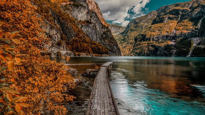 Wooden walkway on a lake with mountains in autumn