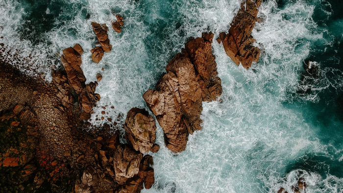 Aerial view of ocean waves crashing on rocky coastline