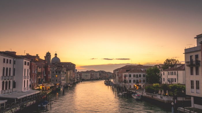 Venice canal at sunset with boats and buildings