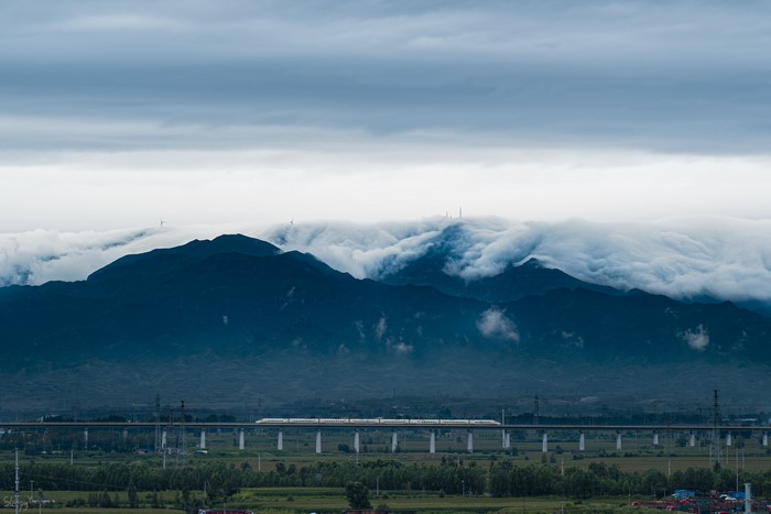 Train on a bridge with mountains and clouds in China