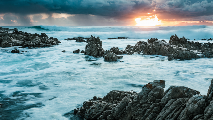 Long exposure of waves crashing on rocks at sunset in South Africa