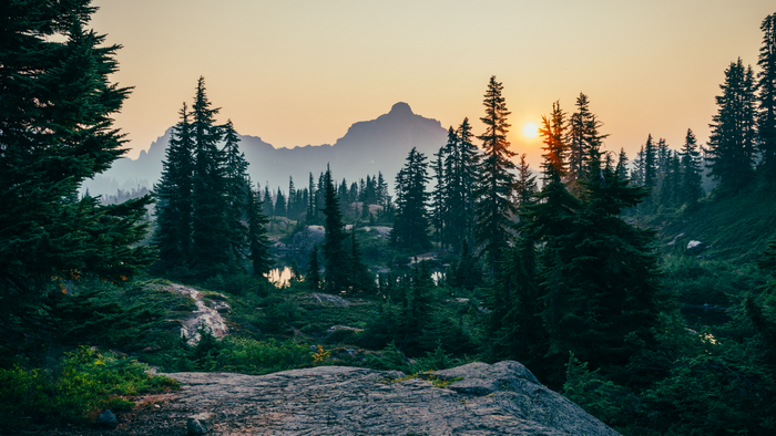 Sunset over mountains and evergreen trees with a lake