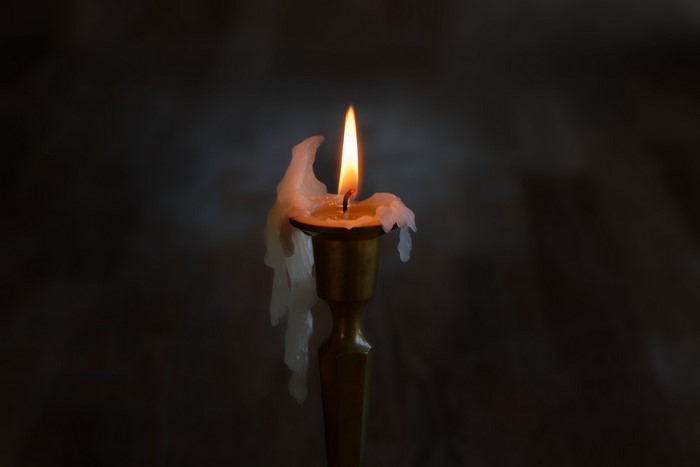 Burning candle with dripping wax in a candlestick