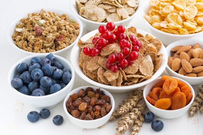 Bowls of cereal, berries, nuts, and dried fruit