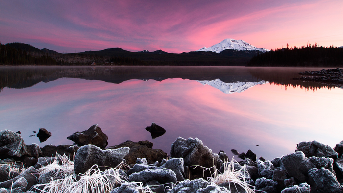 Snowy mountain reflected in a lake at sunset