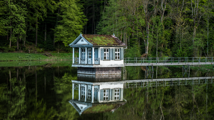 House on a lake with forest and bridge in Switzerland