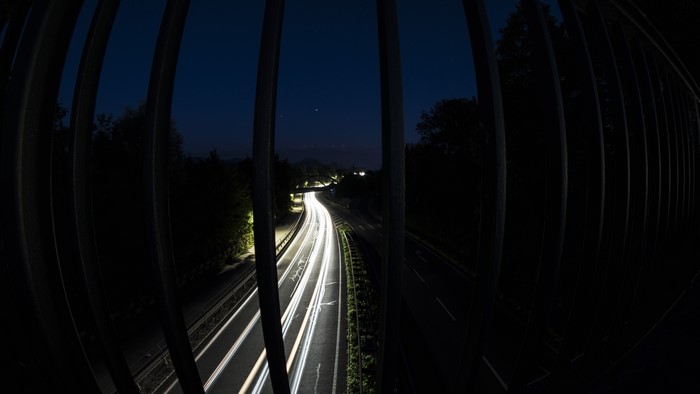 Long exposure of highway at night through fence