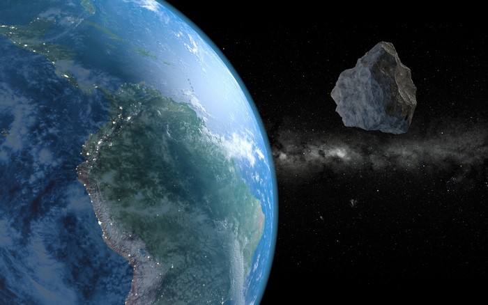 Earth and asteroid in space with Milky Way
