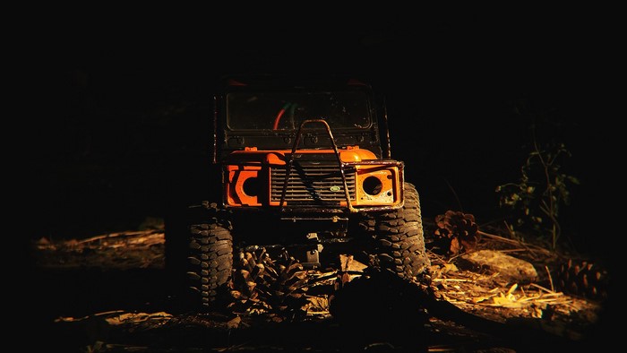 Orange Land Rover Defender offroad vehicle at night