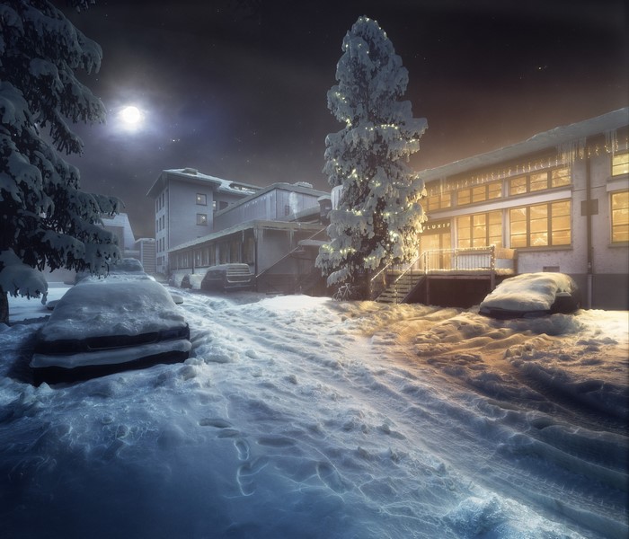 Snow-covered cars and buildings at night with Christmas lights