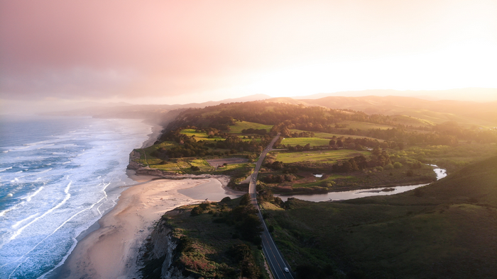 Aerial view of a coastal road and ocean at sunset